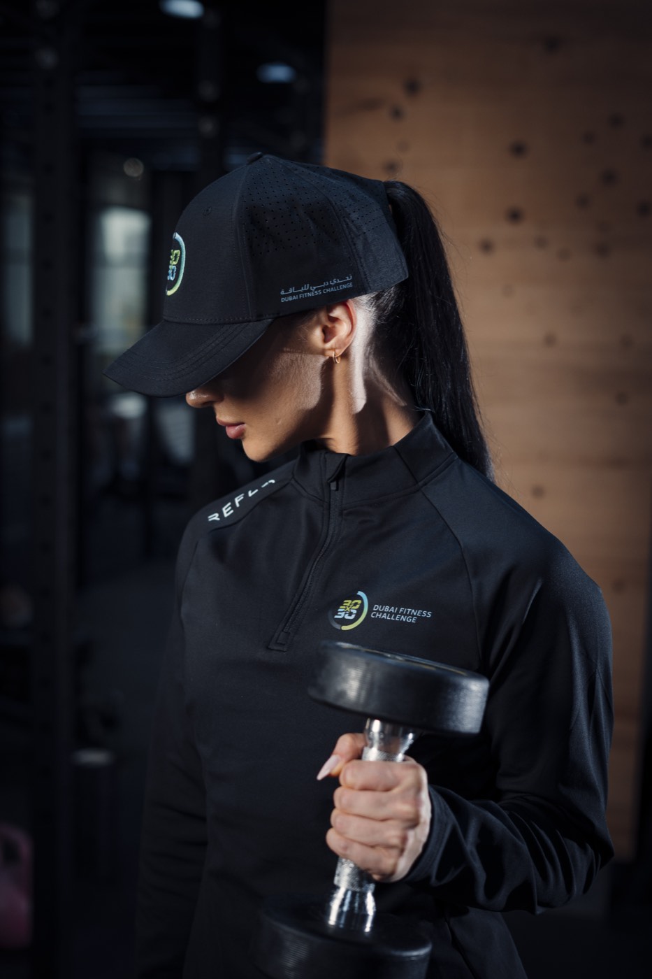 Close crop of a black quarter-zip and cap carrying the Dubai Fitness Challenge logo